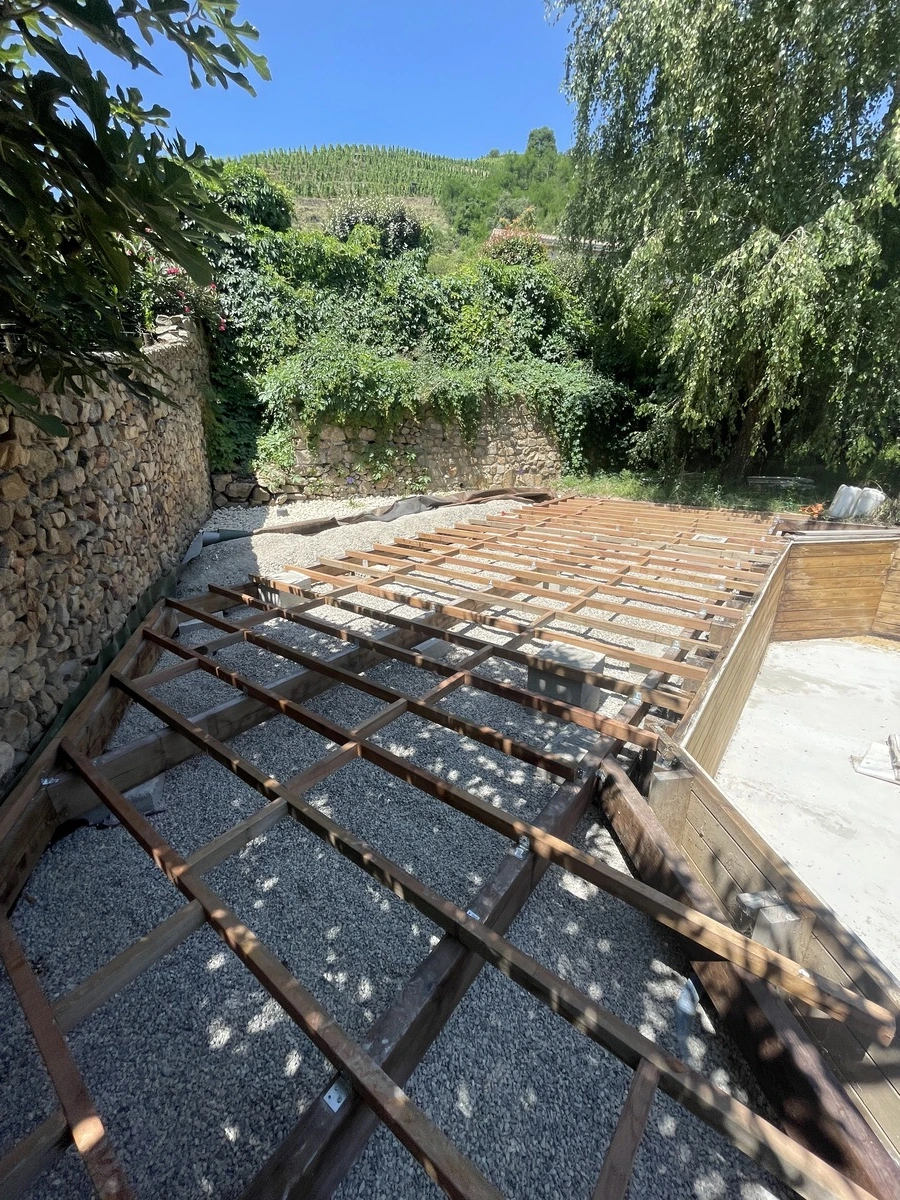 Structure en bois en cours d'installation pour une terrasse, montrant les étapes initiales d'un projet d'aménagement extérieur.