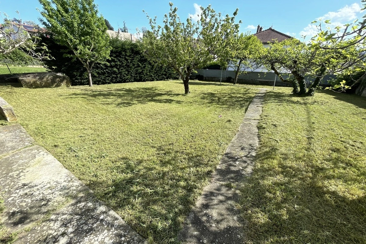 Jardin aménagé avec des arbres fruitiers et une pelouse bien entretenue, démontrant un exemple d'aménagement paysager résidentiel.